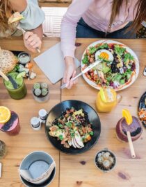 Top view of young people eating brunch and drinking smoothie bowl at  vintage bar - Students having a lunch and chatting in trendy restaurant - Food trends concept - Focus on center tab